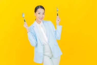 Güzel Asyalı bir kadının portresi kaşıkla ve çatalla gülümsüyor.