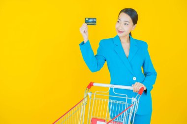 Renkli arka planda süpermarketten alınmış market sepetiyle gülümseyen güzel Asyalı kadın portresi.