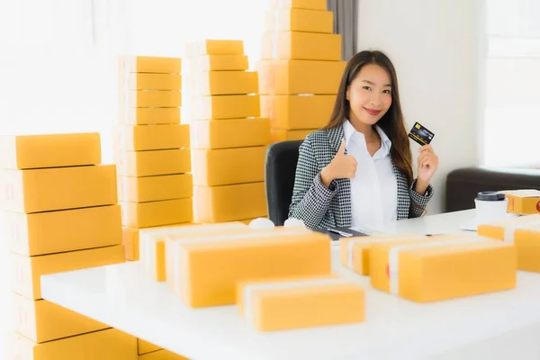 Portrait beautiful young asian woman work from home with credit card and cardboard box ready for shipping of shopping online