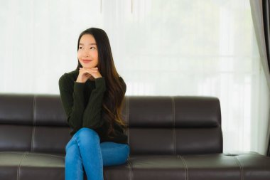 Güzel bir portre. Genç Asyalı kadın. Oturma odasındaki kanepede rahatla.