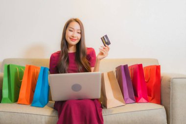 Güzel Asyalı bir kadının portresi. Alışveriş torbalarıyla gülümsüyor.