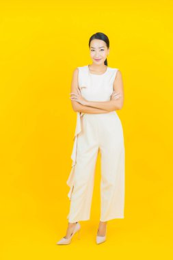 Asyalı güzel bir kadının portresi. Sarı arka planda hareketli gülümsüyor.