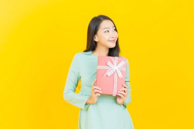 Güzel bir Asyalı kadının portresi. Arka planda kırmızı hediye kutusuyla gülümsüyor.