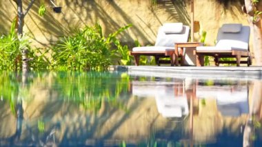 Otelde tatil için yüzme havuzunun etrafında güneşli yataklar.