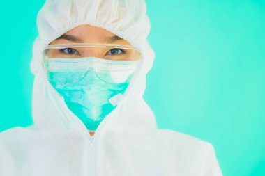 Güzel, genç Asyalı doktor kadın portre. Koronavirüsten ya da mavi arka planda kovid19 'dan korunmak için ppe ya da kişisel koruyucu ekipman takıyor.