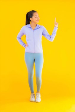 Sarı izole edilmiş arka planda spor giysili güzel Asyalı kadın portresi egzersize hazır.