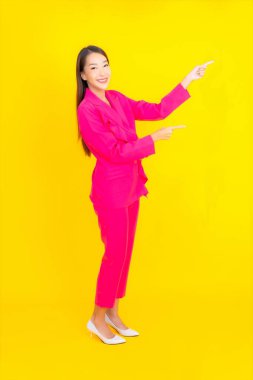 Güzel bir Asyalı kadın sarı arka planda gülümsüyor.