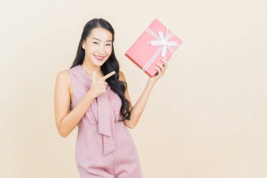 Güzel bir Asyalı kadının portresi. Arka planda kırmızı hediye kutusuyla gülümsüyor.