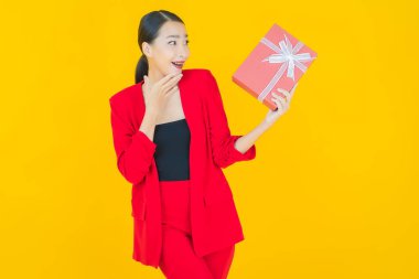 Güzel bir Asyalı kadının portresi. Arka planda kırmızı hediye kutusuyla gülümsüyor.