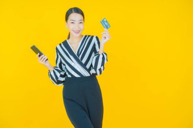 Renkli arka planda akıllı cep telefonuyla güzel Asyalı kadın gülümsemesi