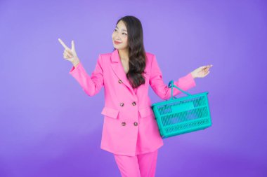 Renkli arka planda süpermarketten alınmış market sepetiyle gülümseyen güzel Asyalı kadın portresi.