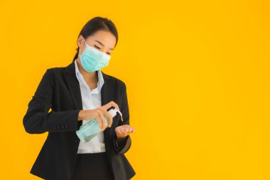 Güzel bir iş kadını portresi. Maske takıyor. Korunmak için alkol jeli kullanıyor.