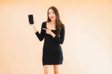 Güzel Asyalı genç bir kadının portresi mutlu bir şekilde gülümsüyor renkli arka planda akıllı cep telefonu kullan