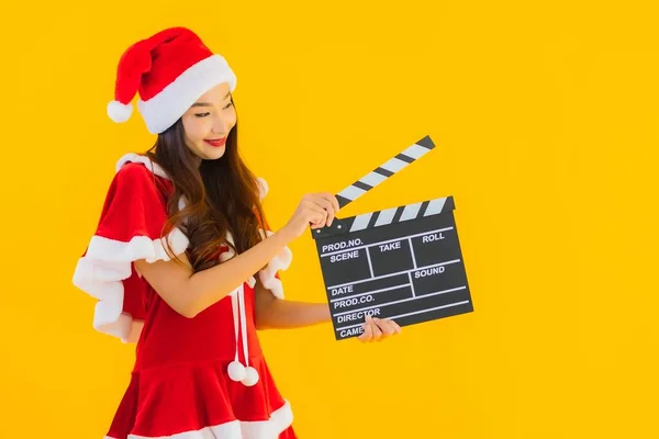 Portrait beautiful young asian woman wear christmas clothes and hat show movie scene cutter plate on yellow isolated background