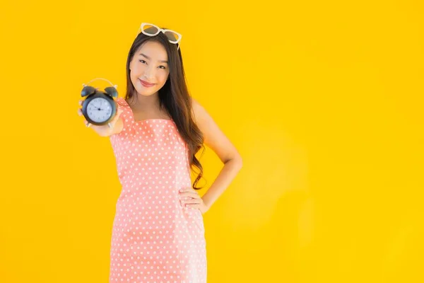肖像美しい若いアジアの女性ショーアラームまたはクロック上の黄色隔離された背景 — ストック写真