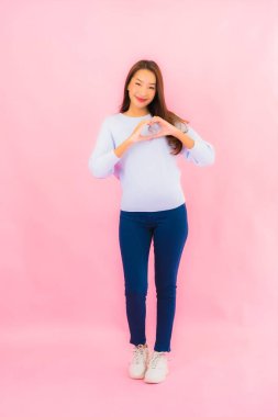 Portrait beautiful young asian woman smile with action on pink isolated background