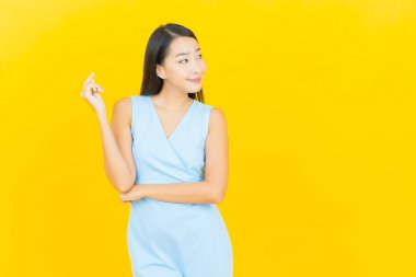 Asyalı güzel bir kadının portresi. Sarı arka planda hareketli gülümsüyor.