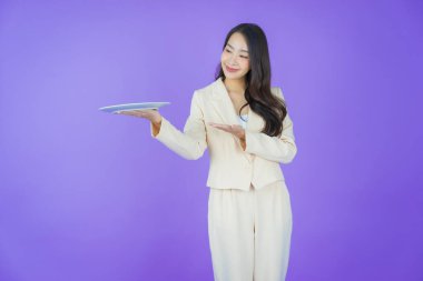 Güzel Asyalı bir kadının portresi. Arka planda boş tabak tabağıyla gülümsüyor.