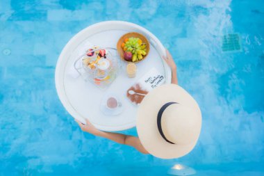 Güzel bir Asyalı kadın portresi. Öğleden sonra çayıyla ya da kahvaltısıyla otel havuzunda yüzer.