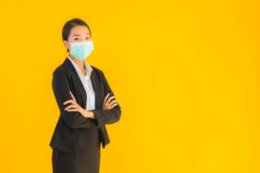 Güzel genç iş kadını portresi Korunmak için maske takıyor 19 koronavirüs sarı izole arka planda