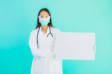 Mavi izole edilmiş arka planda boş ilan panosuyla güzel Asyalı doktor kadın portresi.