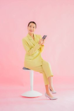 Güzel Asyalı iş kadını portresi. Arka planda kahve fincanı ve akıllı cep telefonu kullanıyor.