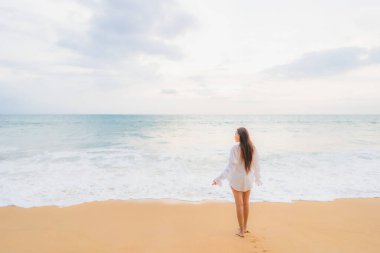 Güzel bir Asyalı kadın portresi deniz kenarında tatil yaparken rahatlar.