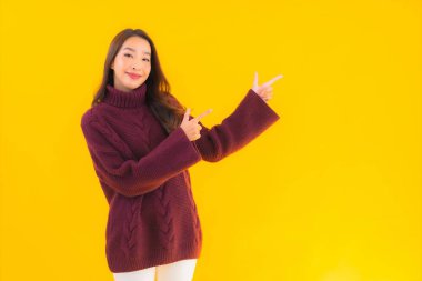 Güzel Asyalı kadın gülümsüyor. Sarı izole edilmiş arka planda başka bir eylemde mutlu.