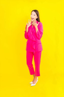 Güzel bir Asyalı kadın sarı arka planda gülümsüyor.