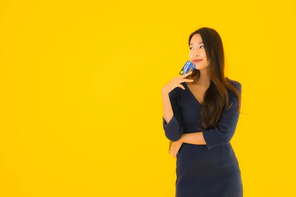 亚洲年轻貌美的女性形象 拥有智能手机 手机和信用卡 背景是黄褐色的 — 图库照片