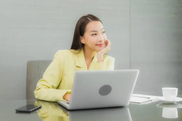 在室内的工作台上 年轻美丽的亚裔女性正在使用装有智能手机的电脑笔记本电脑 — 图库照片