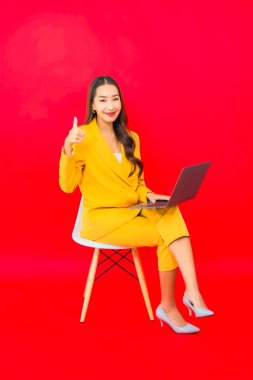 Portre güzel genç iş kadını Asyalı kadın kırmızı arka planda bilgisayar bilgisayarı kullanıyor