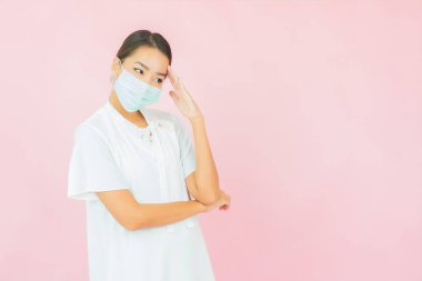 Güzel bir Asyalı kadın, pembe arka planda Covid19 'u korumak için maske takıyor.