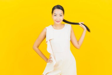 Asyalı güzel bir kadının portresi. Sarı arka planda hareketli gülümsüyor.