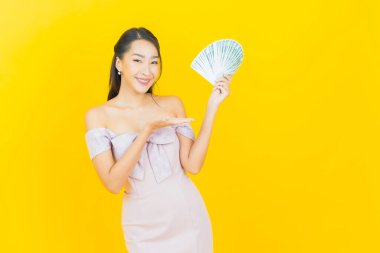 Asyalı güzel bir kadının portresi. Renkli arka planda bol para ve parayla gülümsüyor.