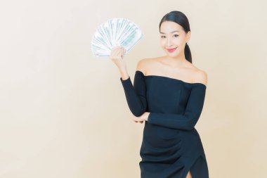 Asyalı güzel bir kadının portresi. Renkli arka planda bol para ve parayla gülümsüyor.