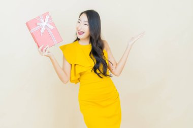 Güzel bir Asyalı kadının portresi. Arka planda kırmızı hediye kutusuyla gülümsüyor.