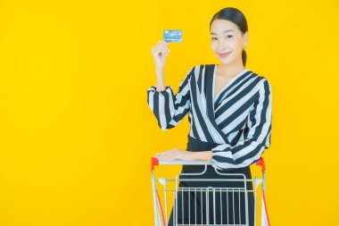 Renkli arka planda süpermarketten alınmış market sepetiyle gülümseyen güzel Asyalı kadın portresi.