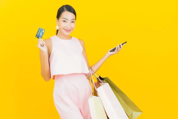 肖像画美しい若いアジアの女性の笑顔でショッピングバッグで黄色の色の背景 — ストック写真