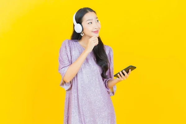 Sarı Arka Planda Müzik Dinlemek Için Kulaklığı Akıllı Telefonu Olan — Stok fotoğraf