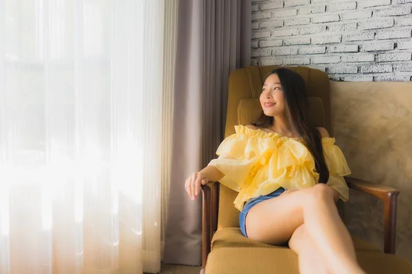 ポートレート若いアジア人女性リラックス幸せな笑顔上のソファ椅子でリビングルームインテリア — ストック写真