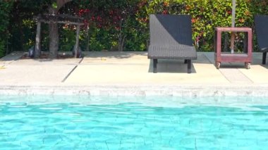 Otelde tatil için yüzme havuzunun etrafında güneşli yataklar.