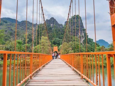 Vangvieng/lao-10 Dec 2017:Unacquainted tourist walking on Suspension bridge cross Nam Song River  at Tham Chang cave Vangvieng City Laos.Vangvieng City The famous holiday destination town in Lao.