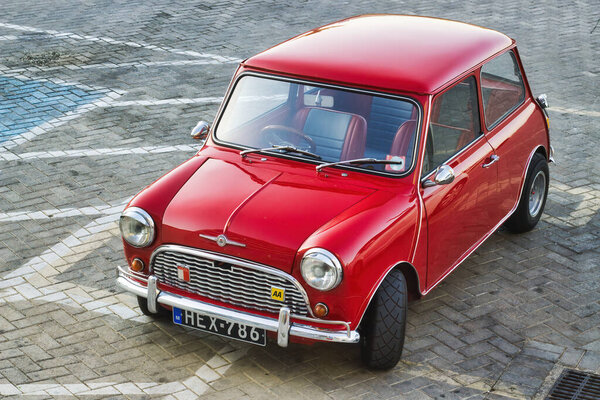 22 May 2022 - Kalkara, Malta: An old bright red Morris Mini Minor parked up in a car park