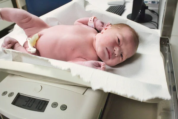 Yeni doğmuş bir bebek hastanedeki doğum koğuşunda dijital ölçekte tartılıyor.