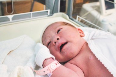 Doğum koğuşundaki hastanede yeni doğmuş bir bebek. Bileğinde plastik bir etiket var.