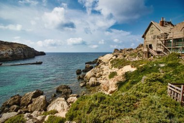 A rocky bay in a fishing village with an old rural wooden hut in the background