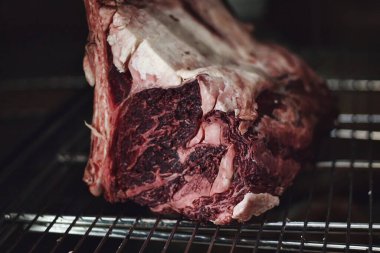 Close-up of raw red tomahawk ribs for juicy steaks on a metallic grill