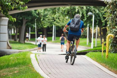 Bisikletçi bisiklet yolunda bir şehir parkında bisiklet sürüyor.