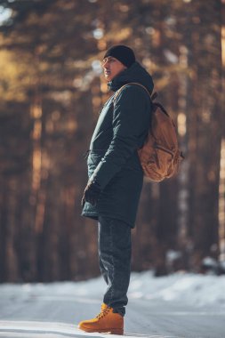 Turist tuvali taşıyan bir adam, kış ormanlarında, ceketli ve kırmızı çizmeli. Yüksek kalite fotoğraf